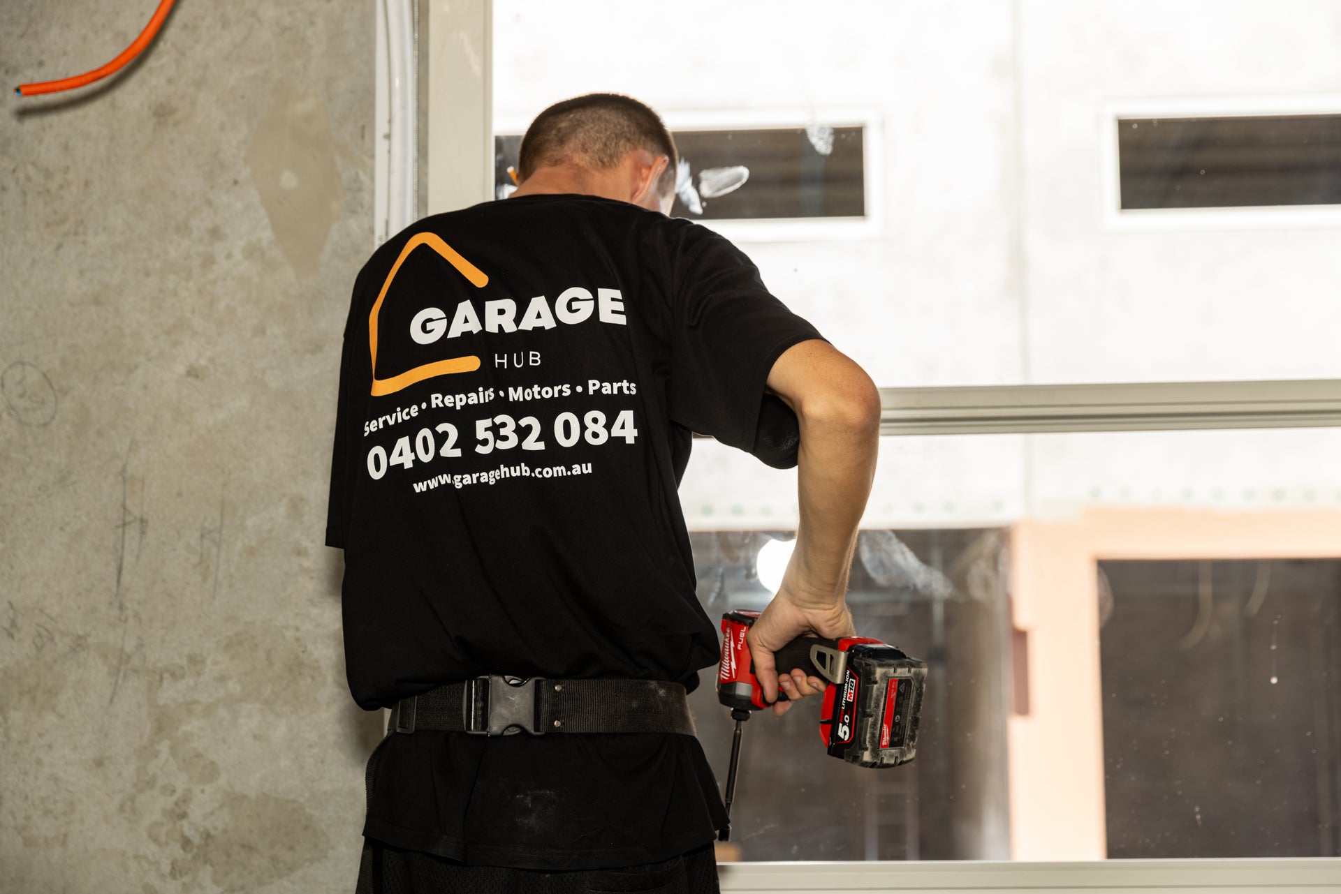 Garage hub technician drilling in some garage door hinges.