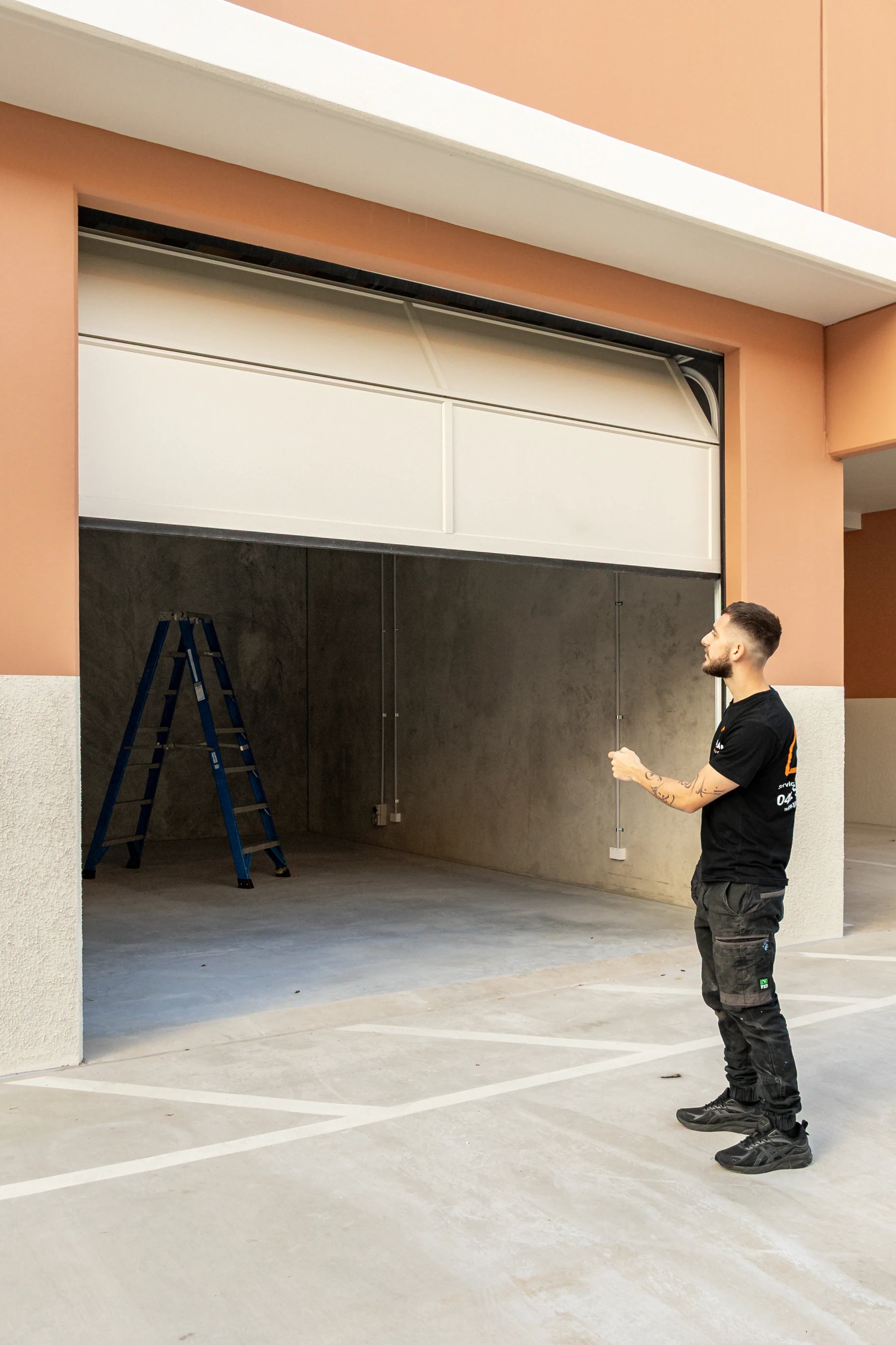 Garage door technician from garage hub in front of a partially open garage door testing garage remote control or opener.
