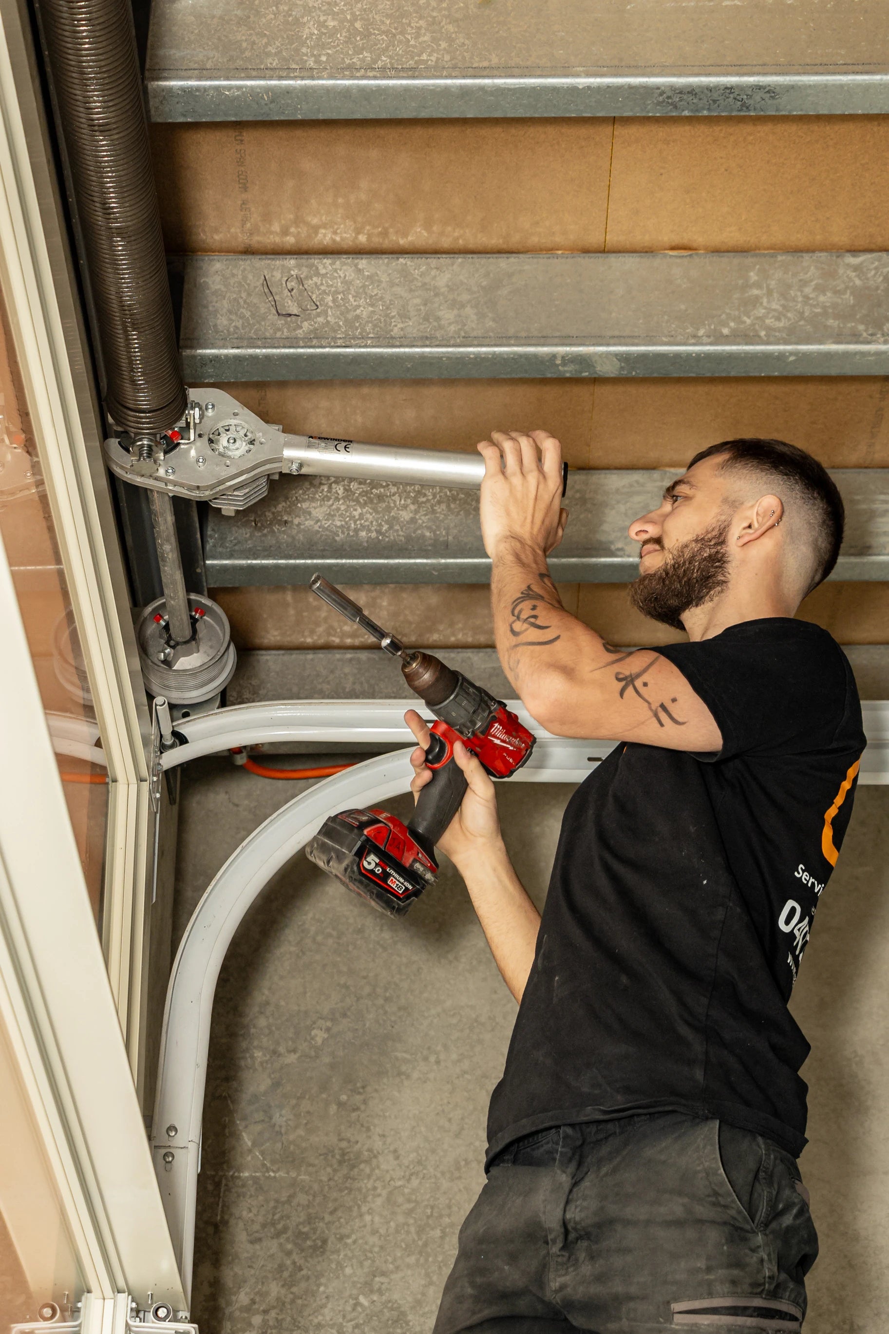 Garage technician working on a spring system with tools in an indoor setting